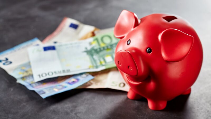 rode spaarpot met daarnaast euro briefjes